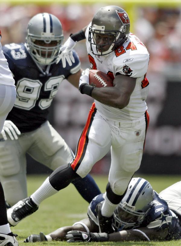 Bucs' running  back  Carnell  Williams  (24)  gets  by  Cowboys'  defensive  players Anthony  Spencer  (93) and  lying on  the  ground   Steve  Octavien.     picture  appears  courtesy  of   ap/photo/ Brian  Blanco  ....................... 